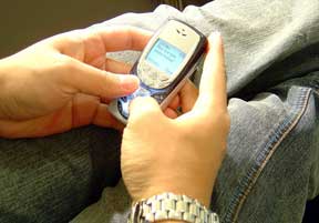 Teenager sending text message on cell phone